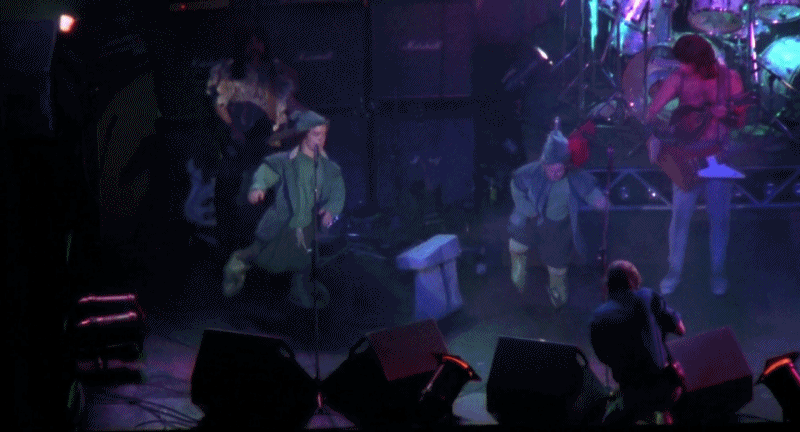 People dance around miniature stonehenges at a Spinal Tap concert